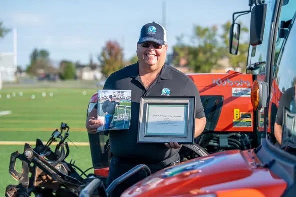 Sean Kelly & Mariam Serkal congratulate Belleville's Ken Hoard, who was named the 2025 Sports Turf Manager of the Year