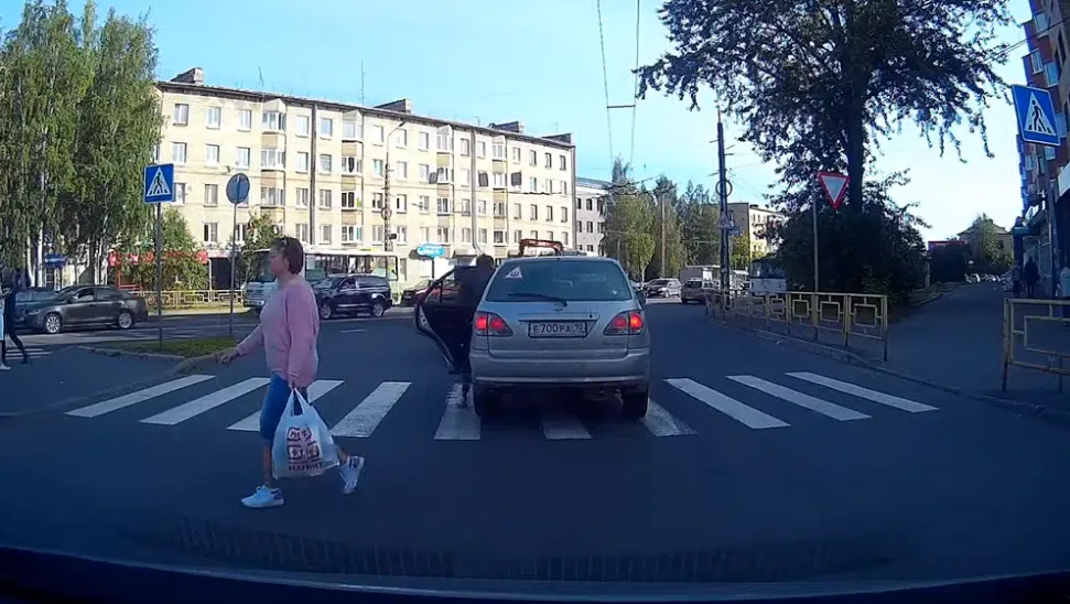 Man climbs through a car blocking crosswalk to cross the street
