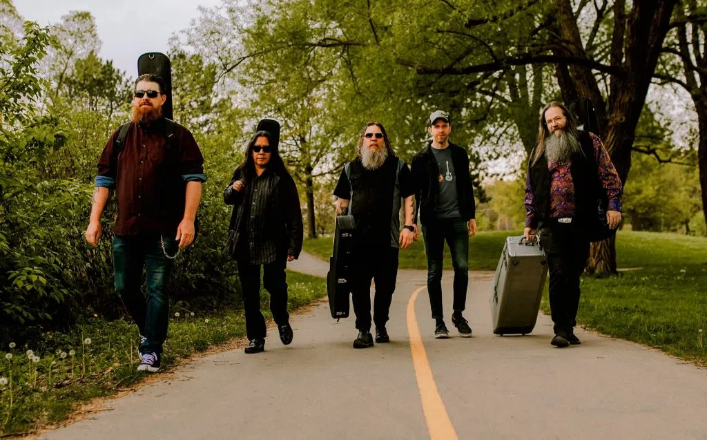 5 men walking on a road with guitars