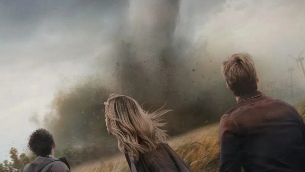 Backs of three individuals looking out at a tornado