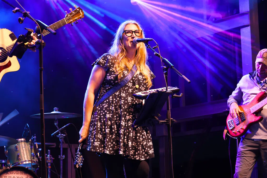 Woman singing on stage with a band