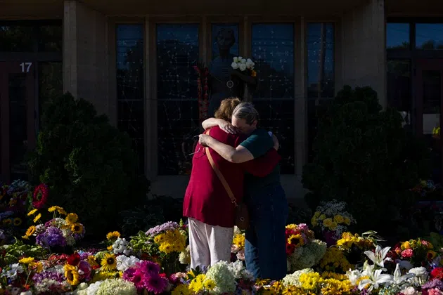 Women embrace at the memorial outside the Annunciation Catholic Church following Wednesday's shooting at the school, Sunday, Aug. 31, 2025, in Minneapolis.