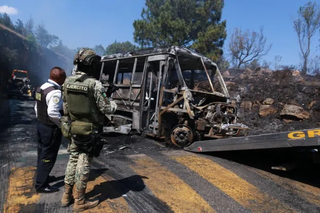 A soldier stands guard by a charred vehicle that was set on fire in Cointzio, Mexico, Sunday, Feb. 22, 2026, amid reports the Mexican Army killed Jalisco New Generation Cartel leader Nemesio Oseguera, known as El Mencho.