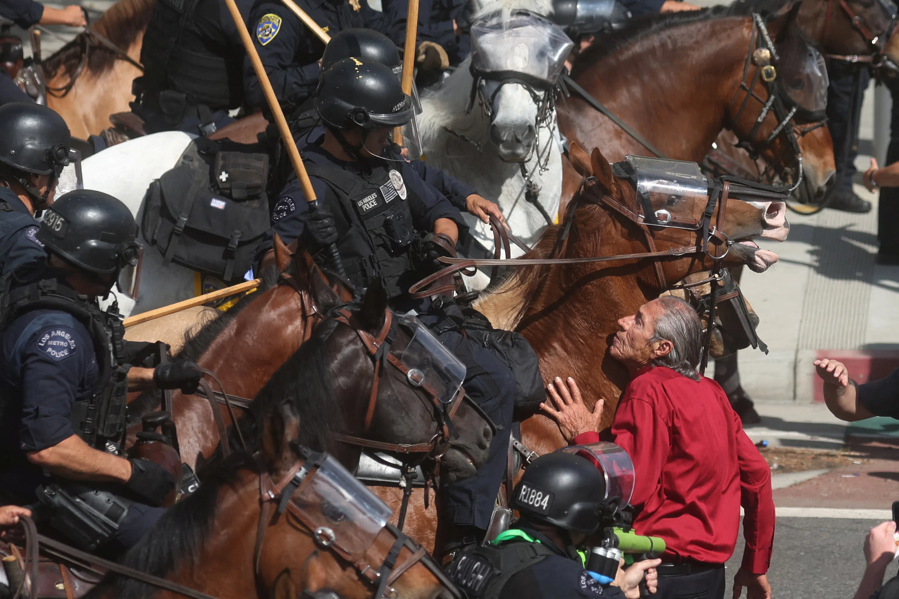 A demonstrator blocks mounted police officers during a "No Kings" protest against U.S. President Donald Trump's policies and federal immigration sweeps, in Los Angeles, California, U.S., June 14, 2025. REUTERS/Pilar Olivares