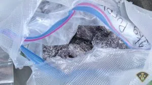 A baggie of dark coloured chunks of a crystalline substance 