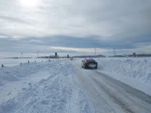 apolice car on a road that is half snow drift