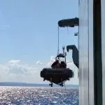 A rescue boat is lowered into the water to save a dummy thrown overboard in a demonstration. 