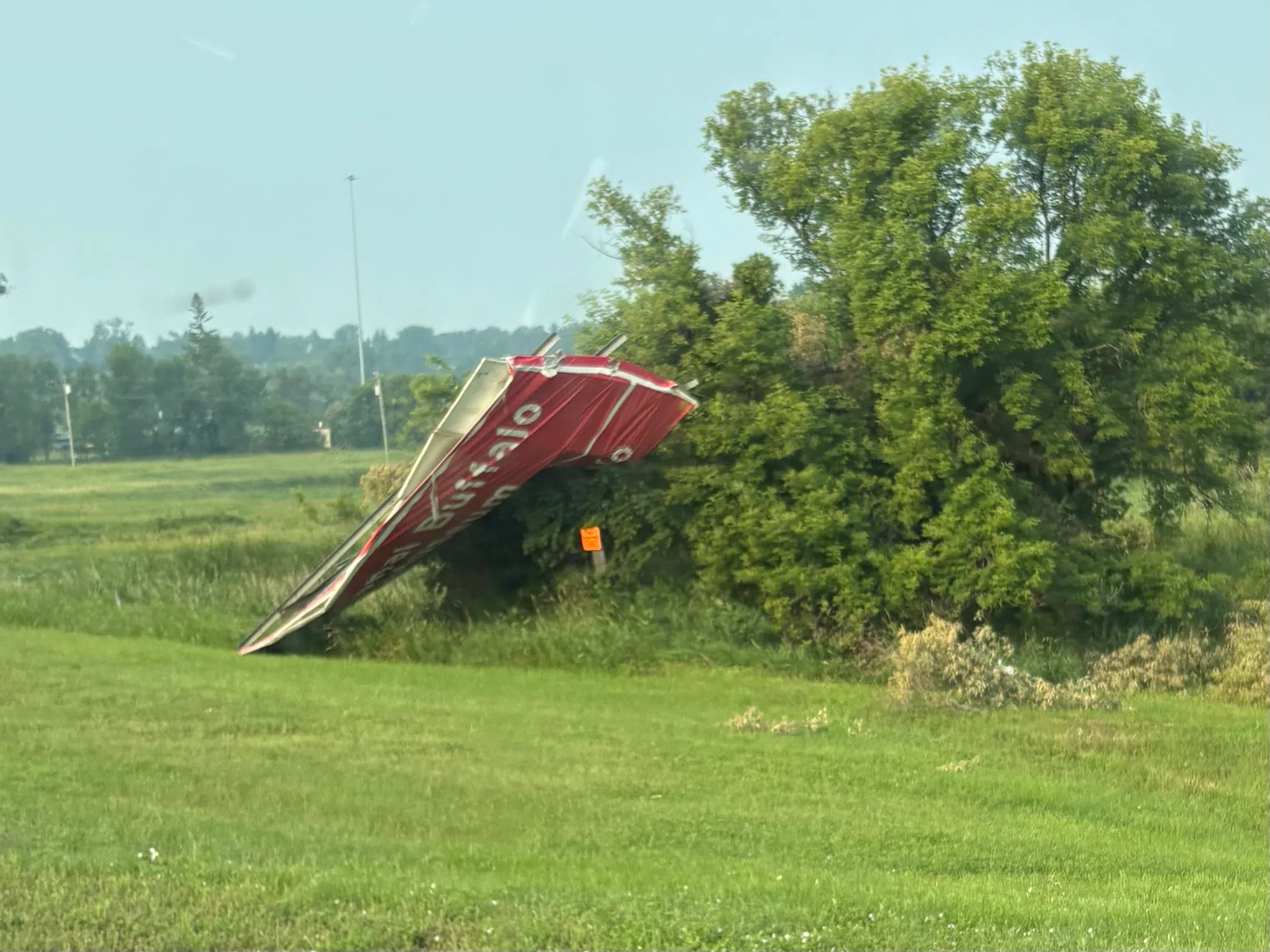 The large metallic red 'National Buffalo Museum' sign toppled on green grass.