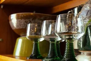 Three drinking glasses with a green ribbed base with measurements on the side.