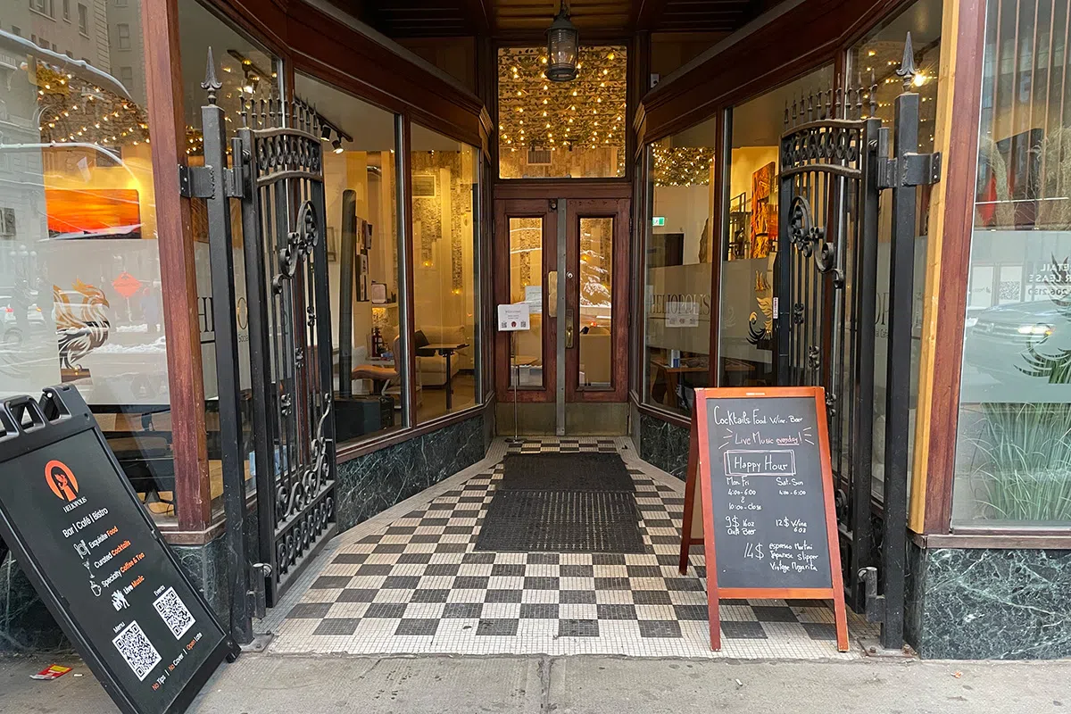 The entryway of Heliopolis Social Cafe featuring signs explaining what the place is all about and logos of the business.