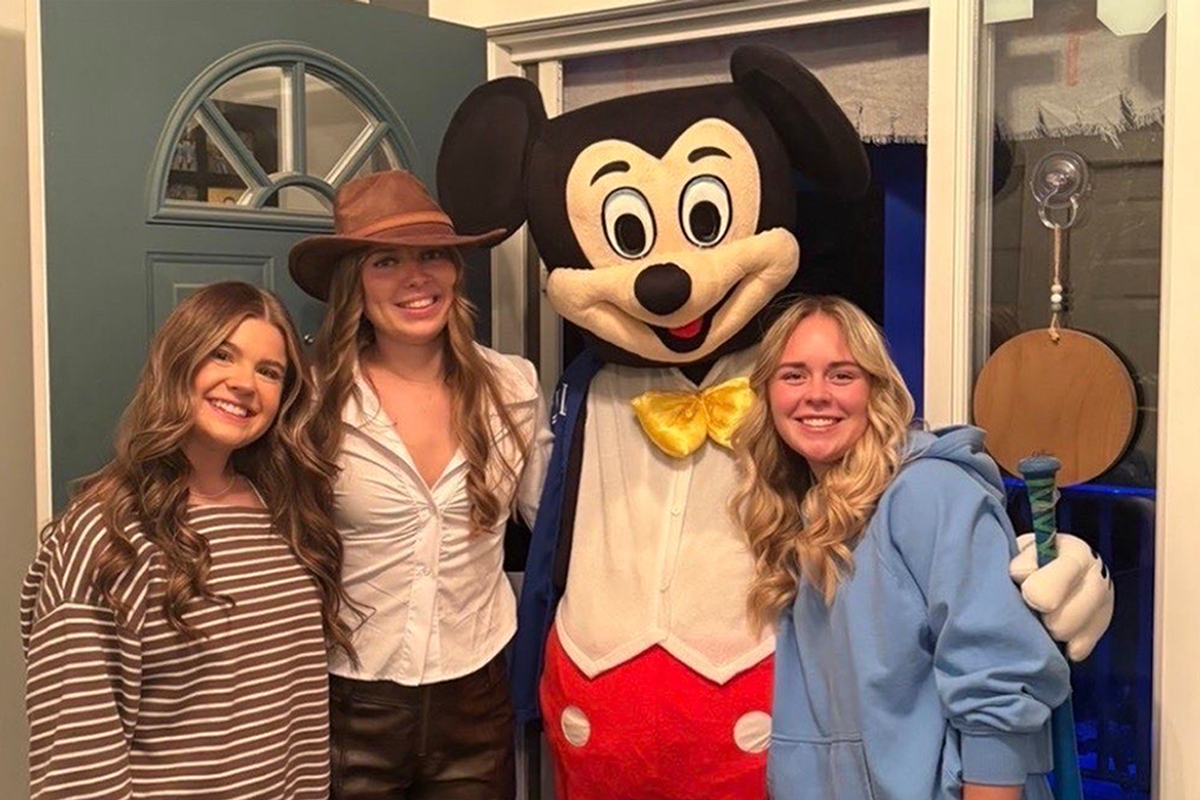 Four people pose together wearing Halloween costumes.