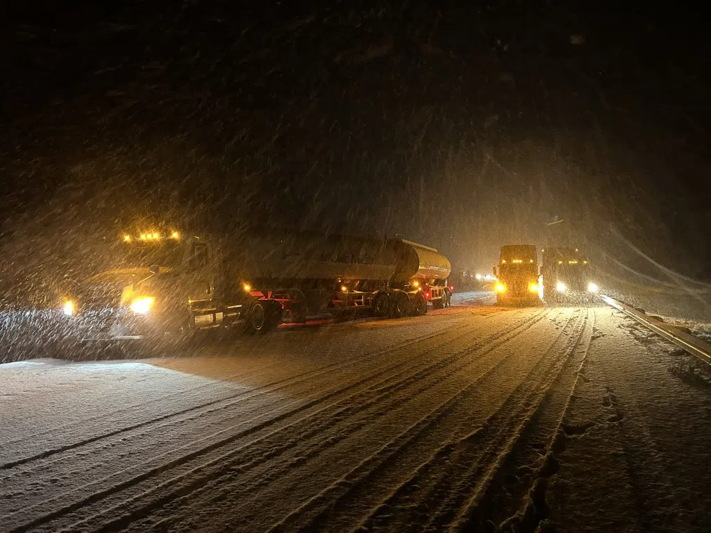 Three trucks stopped on a road covered by snow.