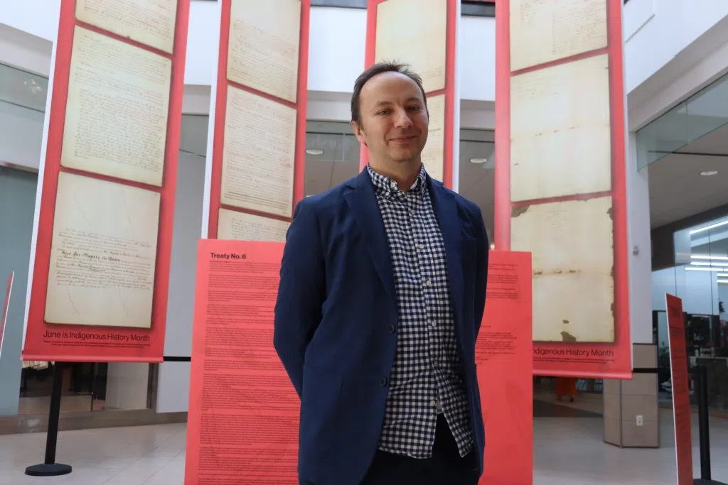 Bo Tarasanko, Marketing Manager at Kingsway Mall standing in front of the Treaty Six Document Display in Kingsway Mall (Photo Credits – Daniel Barker-Tremblay)