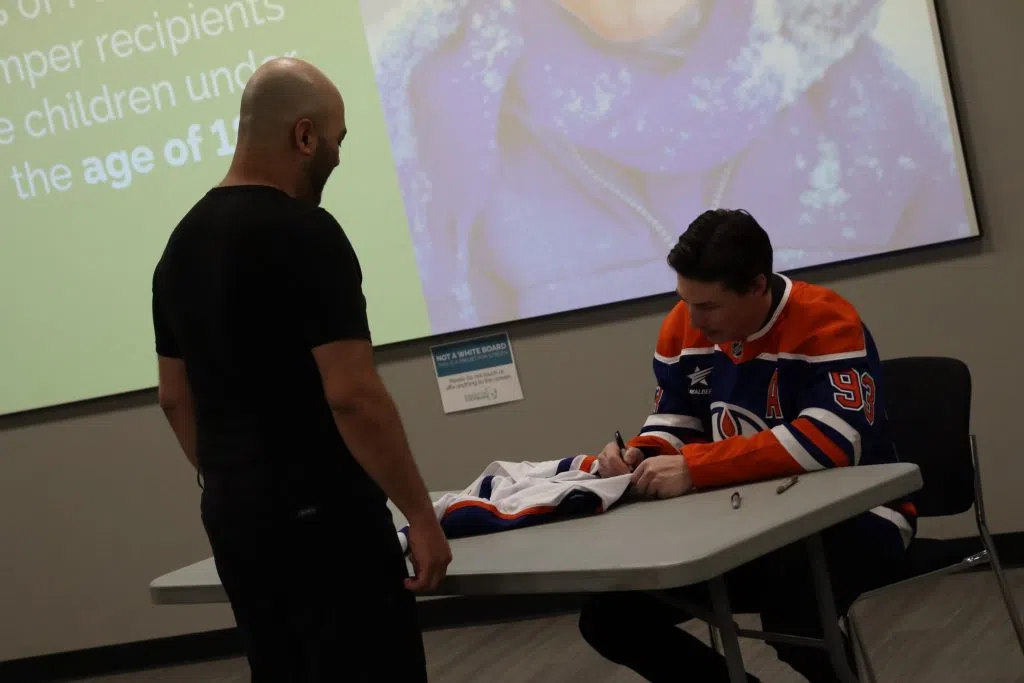 Edmonton Oilers Ryan Nugent-Hopkins signing a jersey at the Edmonton Food Bank (Photo Credits – Daniel Barker-Tremblay)