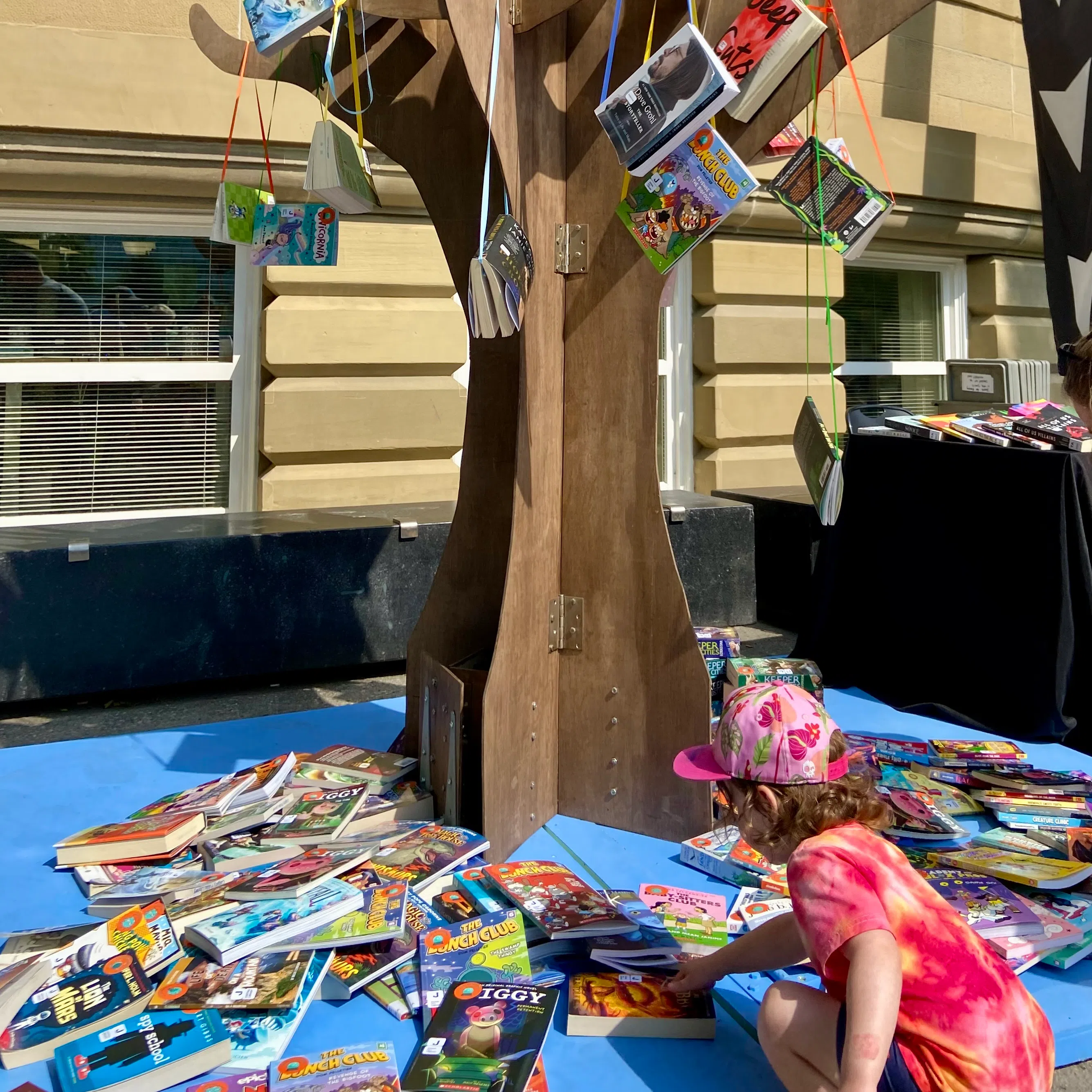 Young reader picking a book from the WordFest Reading Tree at the second annual Reading in the Wild event. Photo by William L Baliko