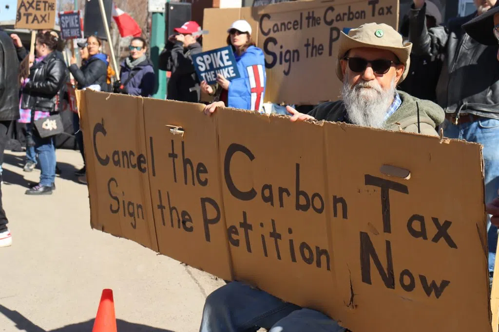 Older Gentlemen holding a sign that reads "Cancel the Carbon Tax Sign the Petition Now" on 124th Street near Jasper Ave (Photo Credits - Daniel Barker-Tremblay)
