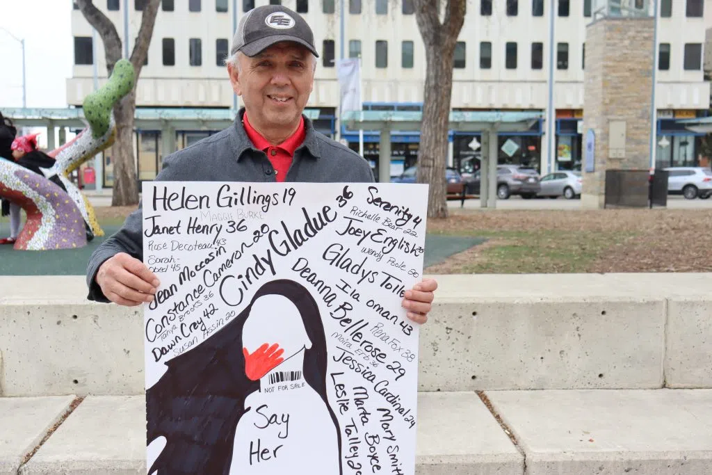 Blaine Knott from NorQuest College holding a MMIW Sign in the Red Dress Day Walk in Churchill Square (Photo Credits - Daniel Barker-Tremblay)