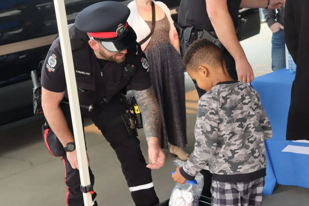 Constable Prandle from the Edmonton Police Service giving a child a gift from the Police Service at the 'Cram A Cruiser' event (Photo Credits - Daniel Barker-Tremblay)