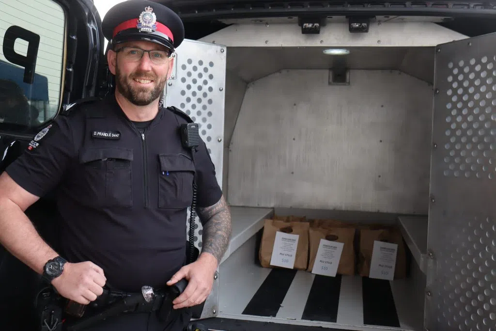 Edmonton Police Constable David Prandle in front of the Cruiser for the 'Cram A Cruiser' event (Photo Credits - Daniel Barker-Tremblay)