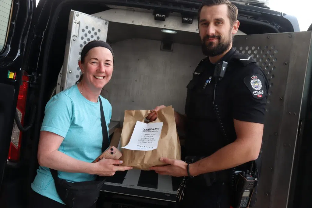 A local costumer handing a donation bag to a Edmonton Police Officer at the 'Cram A Cruiser' event (Photo Credits - Daniel Barker-Tremblay)