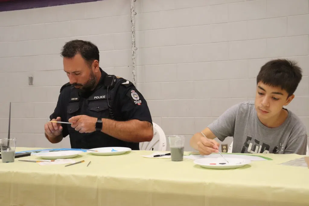 EPS Officer painting with a youth participant in the Oskayak Police Academy at Bent Arrow (Photo Credits - Daniel Barker-Tremblay)