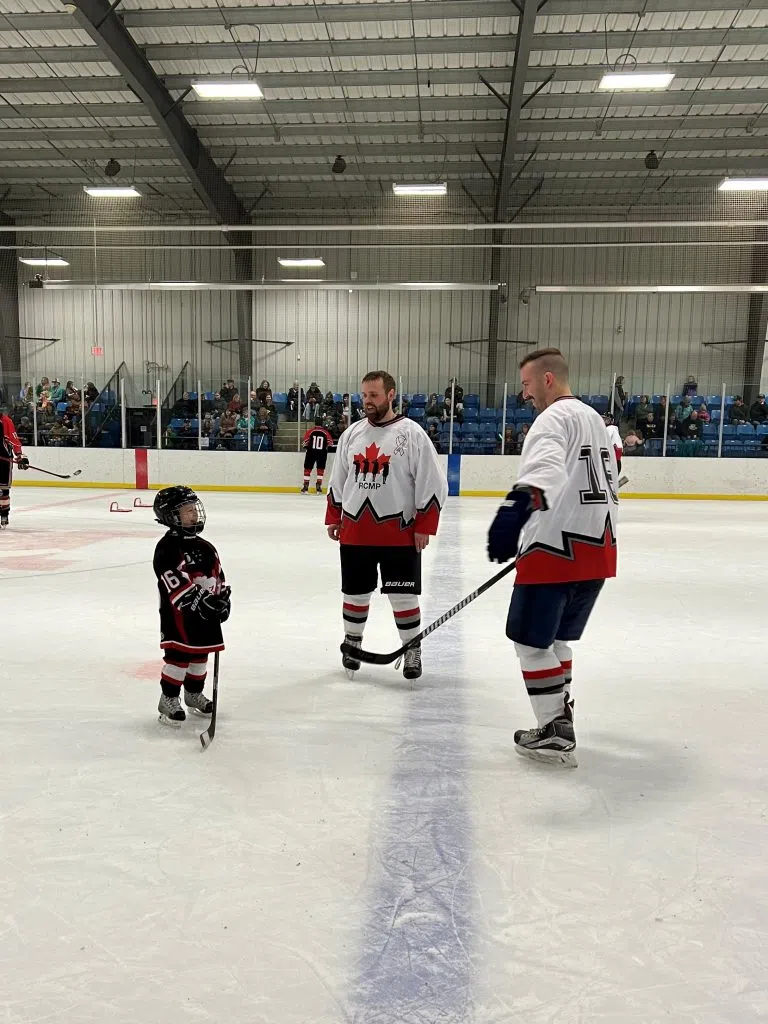 RCMP officers and a Mayerthorpe Minor Hockey Player on the ice (Photo Submitted)