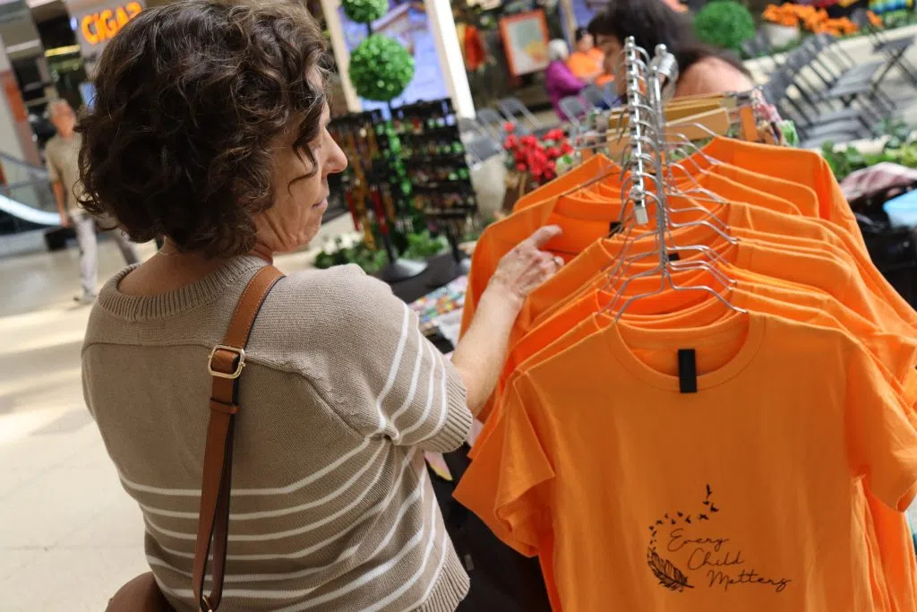 Mall goer checking out the Orange Shirts designed by Tracy Boucher's Daughter at the WEM National Day for Truth and Reconciliation event (Photo Credits - Daniel Barker-Tremblay)