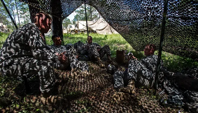 Soldiers of Company A, 1st Battalion, 64th Armor Regiment "Desert Rogues," 2nd Armored Brigade Combat Team, 3rd Infantry Division, try to escape the heat while refreshing their knowledge concerning warrior skills level 1 and the Ranger Handbook, during an exportable combat training center training event located at Camp Shelby, Miss., June 9. At Camp Shelby, the Rogues will act as the opposing force in support of the 278th Armored Cavalry Regiment, a National Guard unit headquartered in Knoxville, Tenn. This event is of great significance in that it is the first time a battalion from the regular Army has acted as OPFOR for a reserve component unit since this practice was stopped after 9/11 due to the regular Army's high rate of deployment. Not only does it signify that the Army is getting back to the way it used to be before the conflicts, but it also signifies a large step towards embracing the total Army concept. The training exercise is scheduled to be more than a month long, and will be finished in the last week of June. (U.S. Army photo by Staff Sgt. Richard Wrigley, 2nd ABCT, 3rd ID, Public Affairs NCO)