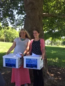 Local substance abuse counselors Aubreeanna Duola (left) and Nicole Haines turn in more than 5,000 signatures, asking Governor Branstad to keep remaining two mental hospitals open.
