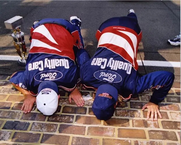 Todd Parrott and Dale Jarrett kissing the Yrad of Bricks at Indianapolis Motor Speedway in 1996.