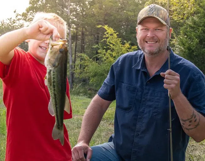 Blake Shelton with a foster child who is holding a fish