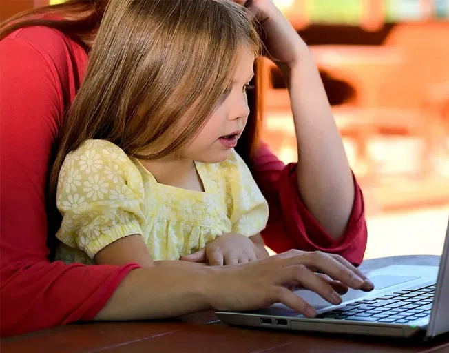 A mom working on a laptop with daughter on her lap