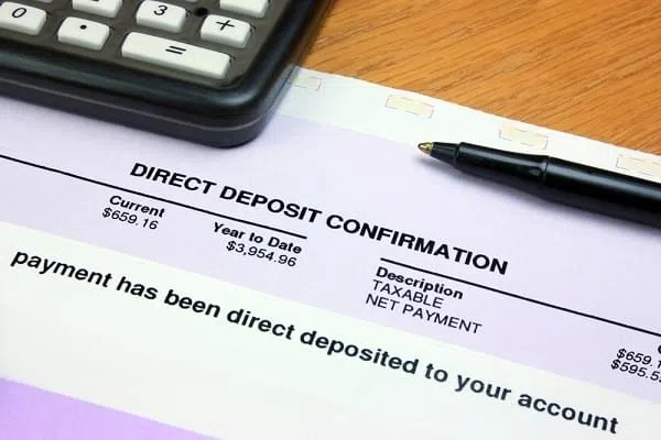 direct deposit summary on a table with a pen and calculator
