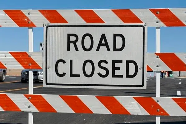 Worn Road Closed Sign in front of street being repaired