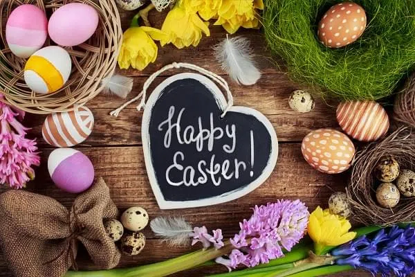 Black board with text - Happy Easter. Colorful Easter Eggs and flowers