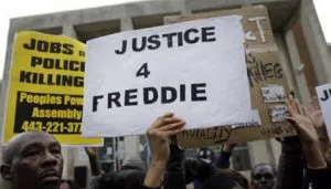 Protestors stand outside of the Baltimore Police Department's Western District police station during a march and vigil for Freddie Gray, Tuesday, April 21, 2015, in Baltimore. Gray died from spinal injuries a week after he was arrested and transported in a police van. (AP Photo/Patrick Semansky)