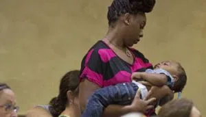 Naomi Clark, 27, holds her sleeping son, 1-year-old Caylei Clark, during services at South Walker Baptist Church in Walker, La., Sunday, Aug. 21, 2016. Clark said she moved to Walker two years ago with her husband who is a truck driver. Her and her two children were with her husband in the truck when the flood struck Walker last week. (AP Photo/Max Becherer)