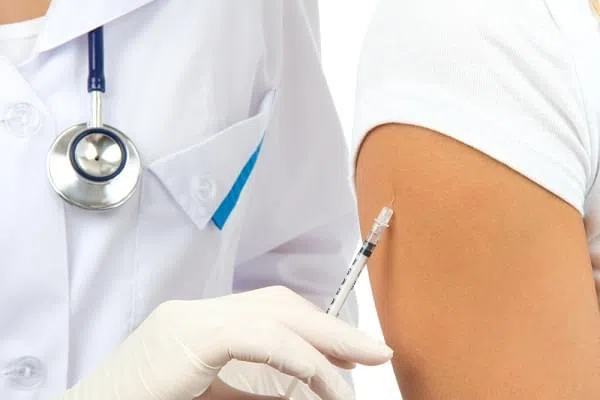 Doctor making insulin or flu vaccination shot by syringe with dose of medicine subcutaneous arm injection inoculation to a woman isolated on a white background
