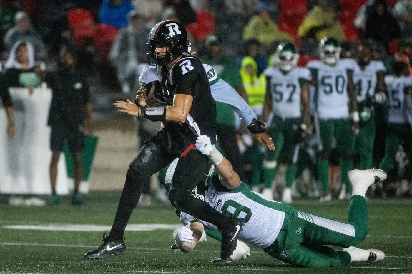 Ottawa Redblacks quarterback Dustin Crum (18) runs with the ball as Saskatchewan Roughriders linebacker Jordan Herdman-Reed (48) attempts a tackle during the first half of CFL action in Ottawa, on Thursday, Aug. 8, 2024. THE CANADIAN PRESS/Spencer Colby