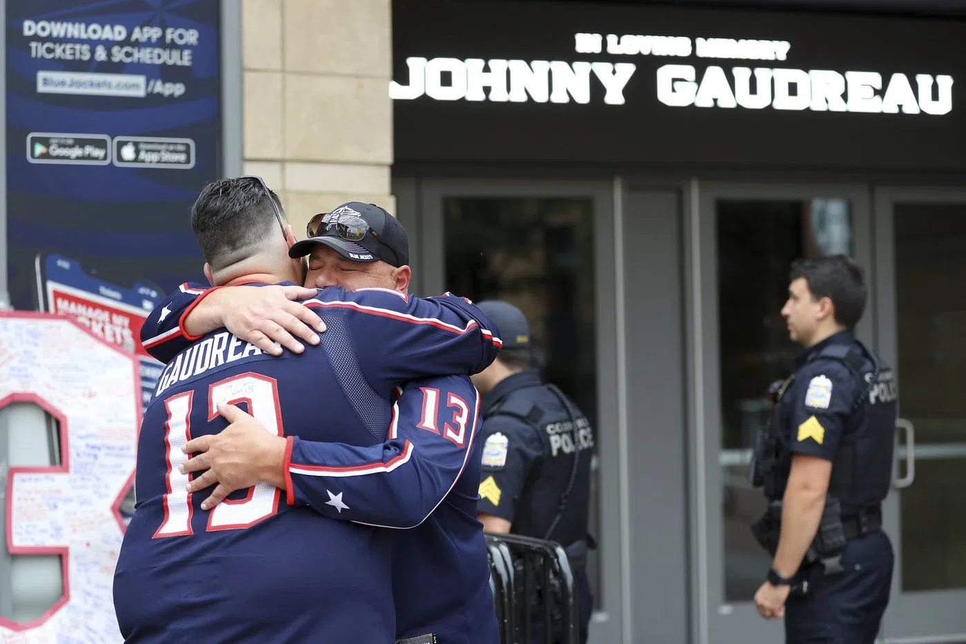 Hylas Stemen, facing, of Columbus, hugs Dave Fetzer at a memorial set up by fans for Blue Jackets hockey player Johnny Gaudreau in Columbus, Ohio, Aug. 30, 2024. Gaudreau, along with his brother Matthew, was fatally struck by a motorist while riding his bicycle on Thursday. (AP Photo/Joe Maiorana)