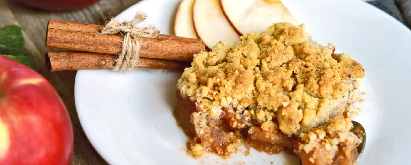 Decorative Apple crisp on plate with a cinnamon stick.