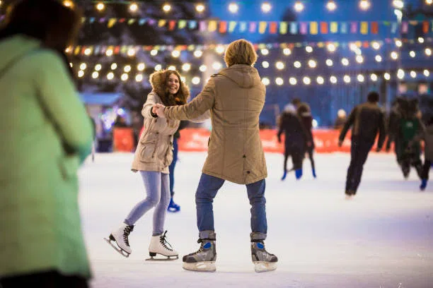 young couple in love caucasian man with blond hair with long hair and beard and beautiful woman have fun, active date skating on ice scene in town square in winter on christmas eve - outdoor skating rink stock pictures, royalty-free photos & images