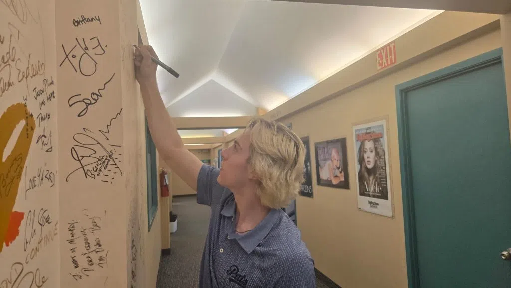 Regina Pats forward Maddox Schultz signs the wall after appearing on The Green Zone. (Britton Gray/980 CJME)