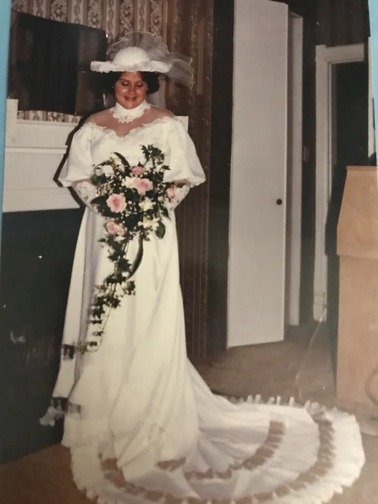 Janette Lee in a wedding dress posing near a piano inside McDonald House