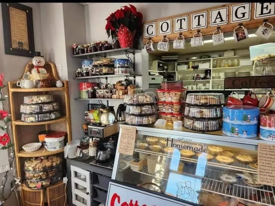 Shelves and counters filled with baked goods, pies, mugs, and coffee in the cozy interior of the Red Paperclip Cottage.