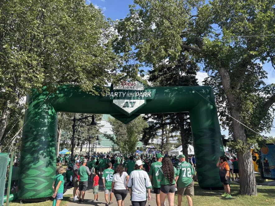 Fans in green jerseys walk under the Party in the Park arch at Mosaic Stadium before the Labour Day Classic.