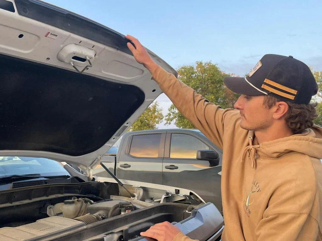 Will Dobson opens the hood of his truck to show where the bullet exited the vehicle.