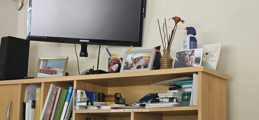 Keith King’s desk with framed photos, including his red 1968 Ford Galaxy convertible, family portraits, and a small white dog.
