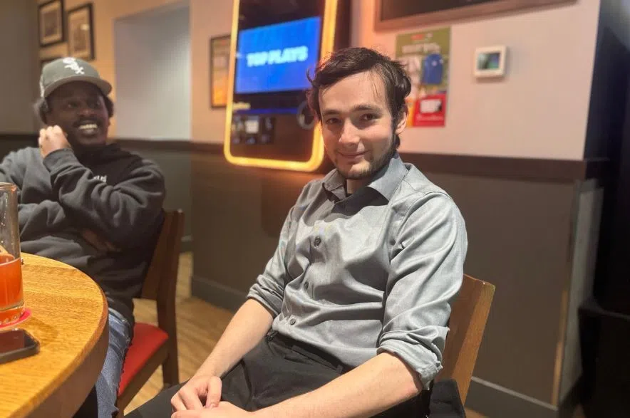 A man in a grey shirt smiles while watching the Blue Jays game inside Boston Pizza in Regina during the ALCS Game 6 watch party.