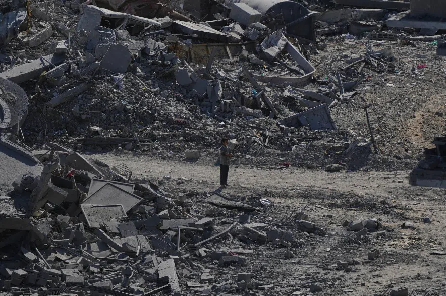 A Palestinian boy stands amid destroyed buildings in Gaza City.